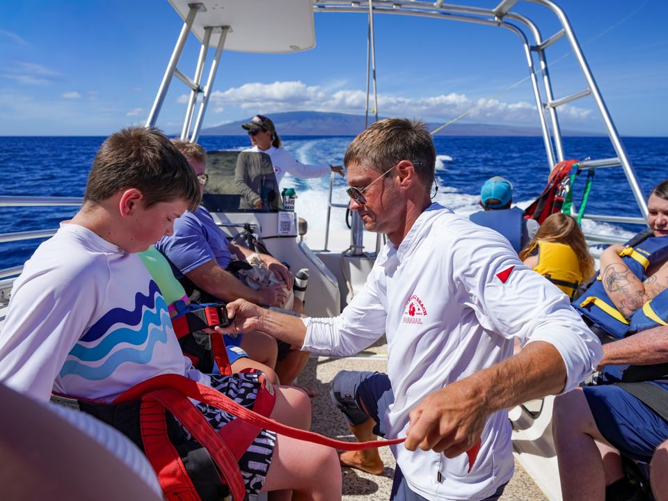 Crew fitting a young flyer's harness on the boat deck