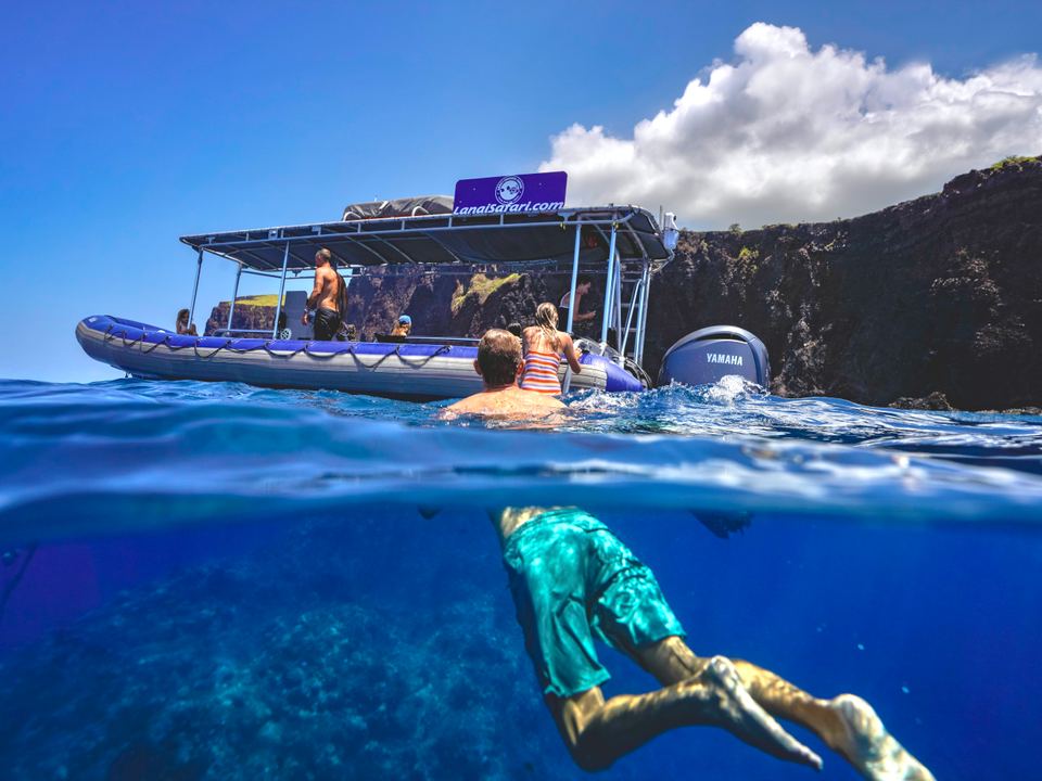 Snorkelers in clear water beside the Lānaʻi Snorkel Safari raft